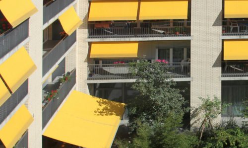 A block of flats with yellow canopies over the balconies.