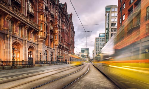 An artistically blurred view of a tram and station in the City of Manchester.