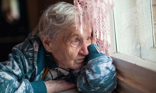 An older lady looking through a window.