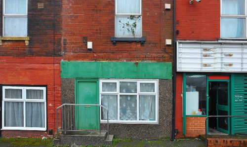 Run-down terraced houses on a street in Leeds with shabby decaying colourful painted walls.