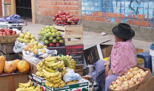 An older woman surrounded by a fruit stand.