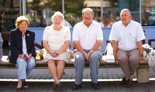 four older people sitting on a bench