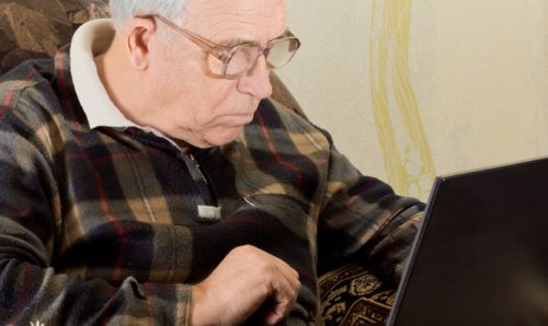 An older man looking at a laptop. 